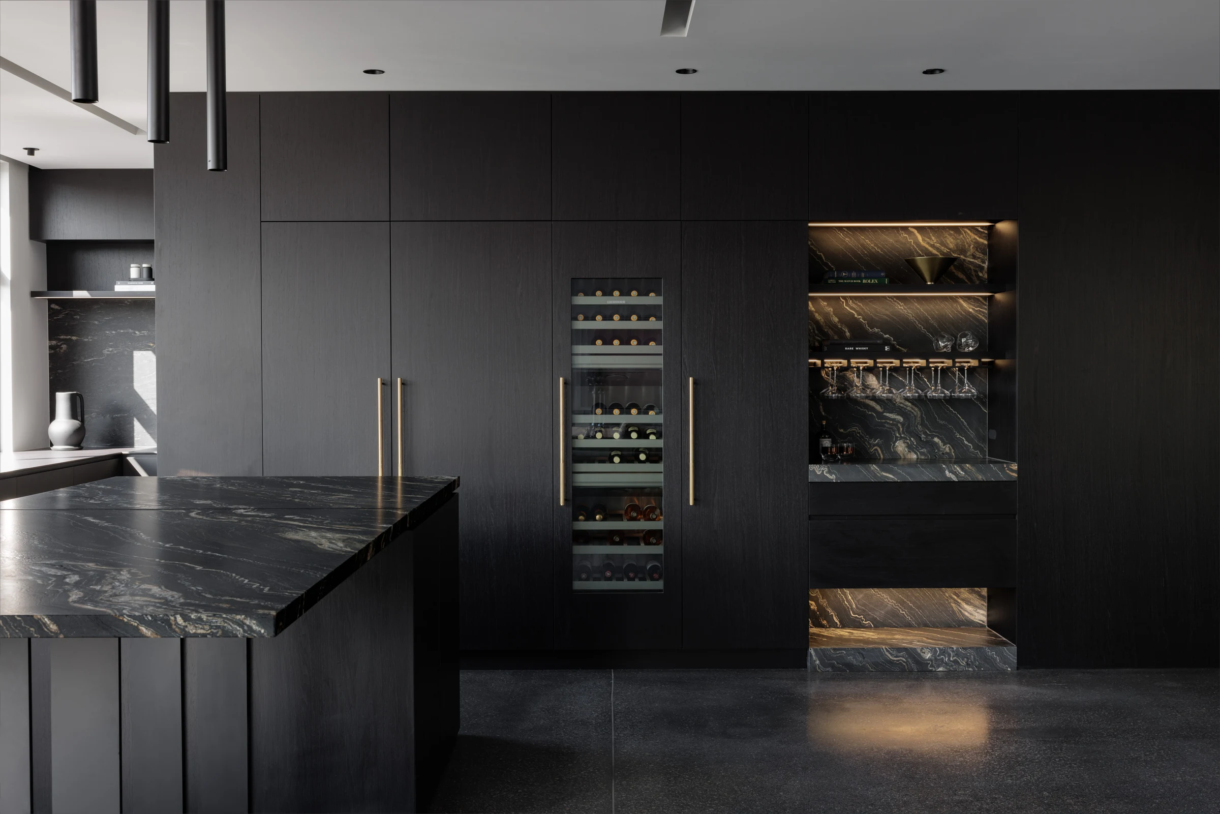 Dark stone, charcoal joinery and illuminated shelving in an Eastern Built project.